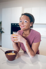 Young dark-skinned woman holding a glass with orange juice