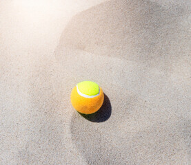 Tennis ball on the sand at the beach close up. Professional sport concept