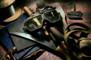 The table is littered with a bunch of old things, construction tools, objects in the workshop. Safety glasses. Close-up.