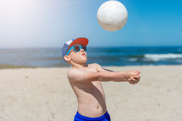 Young boy playing volleyball on beach. Summer sport concept.