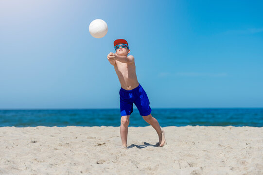Young boy playing volleyball on beach. Summer sport concept.