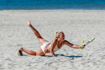 Young girl playing beach tennis on sand. Professional sport concept
