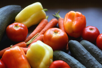 Zucchini, tomatoes, peppers, carrots and cucumbers on dark background. Selective focus.