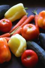 Zucchini, tomatoes, peppers, carrots and cucumbers on dark background. Selective focus.