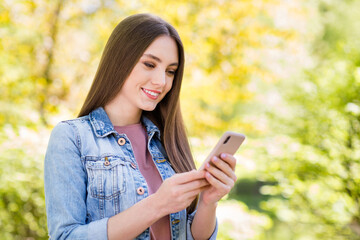 Portrait of attractive focused cheerful girl spending time using device blogging outdoor strolling fresh open air