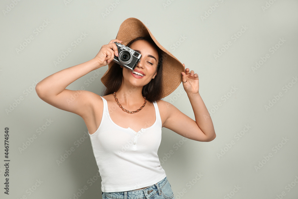 Sticker Beautiful young woman with straw hat and camera on light grey background. Stylish headdress