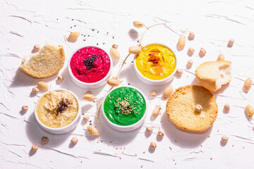 Various hummus dips, the flat lay of hummus in different colors with spinach, beetroot, turmeric and vegetables