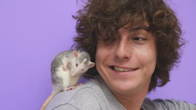 A man with curly hair with a pet rat-mouse on an isolated background in the studio