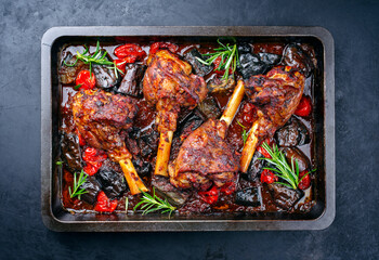 Traditional braised slow cooked lamb shank in red wine sauce with eggplants and tomatoes served as...