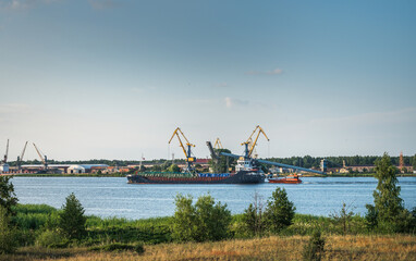 Riga port loading terminal with container ships. Boats and yachts riding on river. Industrial territory meets sustainable environment.
