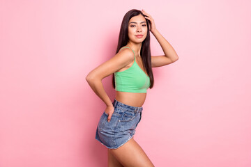 Photo of adorable sweet young lady wear green tank-top standing arm pocket hand head smiling isolated pink color background