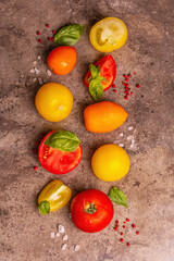 Culinary background with ripe tomatoes and basil leaves sea salt, and pink peppercorn on a stone background