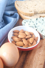 blue cheese, brown bread, egg and almond nut on table.