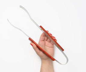 female hand holds tongs with wooden handle against white background,