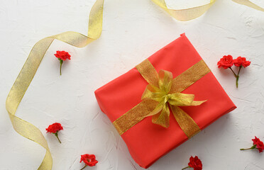 box packed in holiday red paper and tied with a silk ribbon on a background, birthday gift