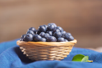 Organic blueberries in a wicker bowl on a napkin with a leaf