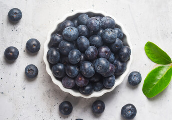 Ripe blueberries on a concrete background with a leaf