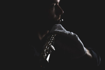 flutist in a black shirt, against a dark background .. male executor on a wooden wind instrument