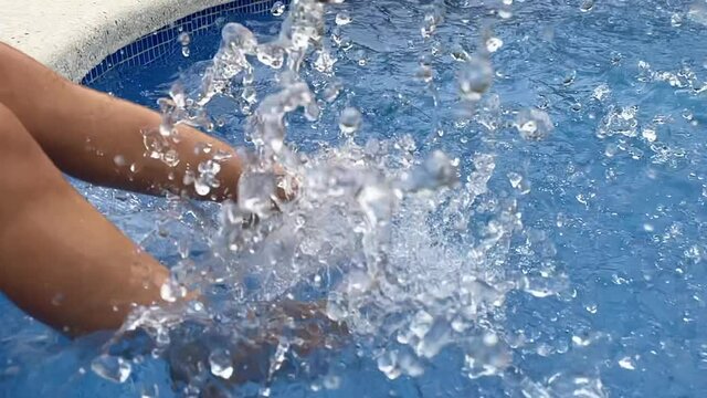 Child splashing feet in swimming pool water
