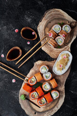 Sushi rolls California and Philadelphia on wooden cut on black background. Concept delivery service. Japan food in eco container. Zero waste packaging. Top view. High quality photo