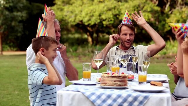 Animation of confetti falling over happy family at birthday party
