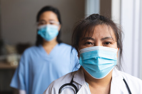 Portrait of two asian female doctors wearing face masks at home