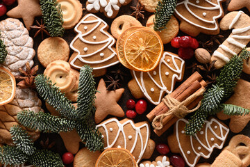 Pattern of Christmas glazed cookies different shapes, cinnamon, anise stars, red berries, orange chips, spruce branches. Festive bakery background. View from above. Flat lay. Xmas holiday.