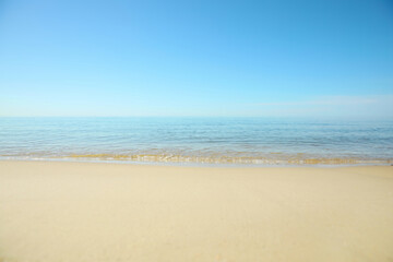 Fototapeta na wymiar Beautiful sandy beach and sea under blue sky, closeup
