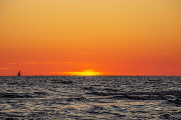 Gorgeous sunset in the Baltic Sea. At the horizon the yacht sails and the ship is about to enter the port.