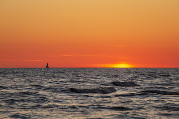 Gorgeous sunset in the Baltic Sea. At the horizon the yacht sails and the ship is about to enter the port.
