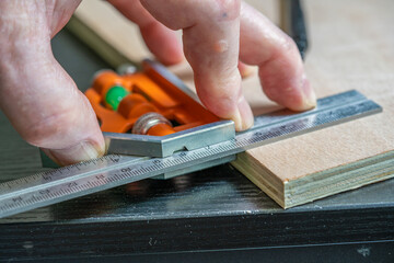 selected focus of measuring a perfect right angle on a piece of plywood using an adjustable calibrated square