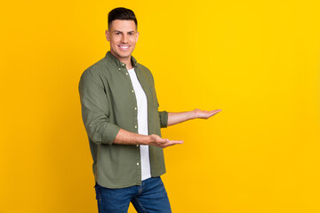 Photo portrait man smiling keeping empty spaces on hands isolated bright yellow color background