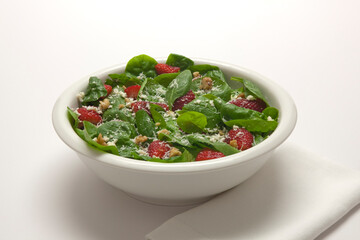 A healthy fresh spinach salad with streawberries, feta cheese, walnuts and a hard parmesan, romano style cheese