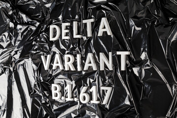 words delta variant B.1.617 laid with silver metal letters on crumpled black plastic bag background...