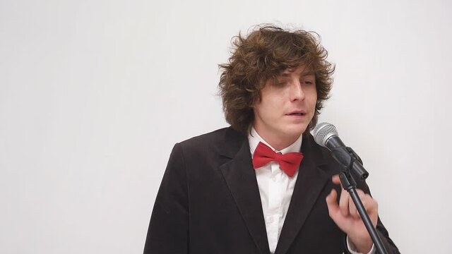 A shy Caucasian man, a speaker with a microphone on an isolated background, a young man is afraid to speak in front of a crowd of people or an audience