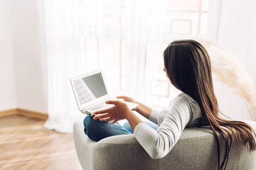 A young girl studies using a laptop, watches a video course of a college university, sitting in a...