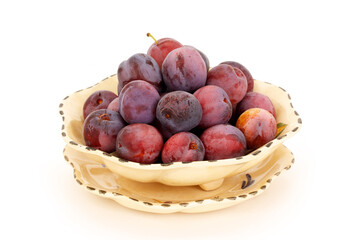 Fresh picked prunes in a bowl on completely white background