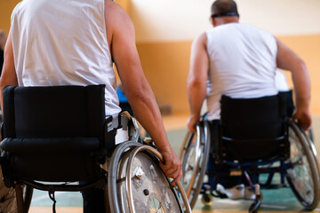 Obraz premium Close up photo of wheelchairs and handicapped war veterans playing basketball on the court