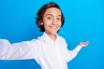 Photo of attractive cute school boy wear formal outfit smiling recording video inviting coming isolated blue color background