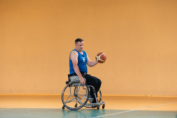 a war invalid in a wheelchair trains with a ball at a basketball club in training with professional sports equipment for the disabled. the concept of sport for people with disabilities
