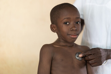 Portrait of an uneasy looking African boy during stethoscope auscultation for diagnostic purposes