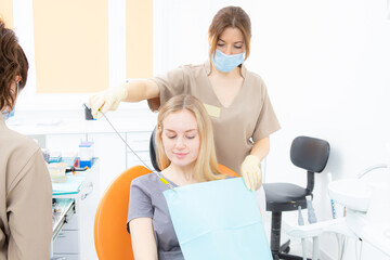 Obraz premium The dentist's assistant puts the protection on the patient before the treatment