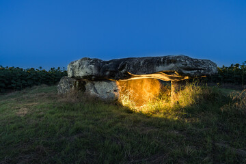 Dolmen lighted at night in a field of sunflowers