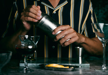 Fototapeta na wymiar man preparing a cocktail in a metal shaker