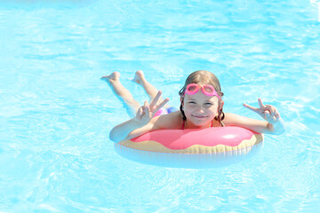 Cute little girl swims in an outdoor pool on an inflatable circle