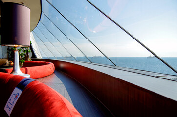 Luxurious observation or panorama lounge with floor to ceiling windows and red velvet arm chairs...