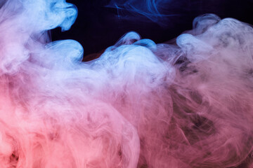 Art photo of colorful smoke moves on black background. Beautiful swirling colorful smoke.