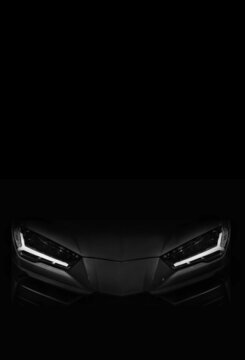 Silhouette of black sports car with LED headlights on black background, copy space