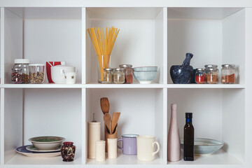 Kitchen utensils and tableware on white shelves. Well organized kitchen concept. Modern interior.