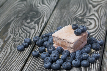 Blueberries are scattered on pine boards. Portion marshmallow. Close-up shot.